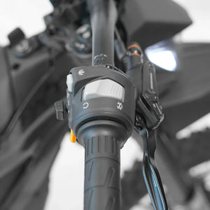 Side view of the eMOTO Strike SRPNT X3 electric motorcycle in black and green, parked on a concrete surface with a blurred urban background.