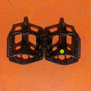 A pair of metal eBike pedals in a rectangular design with textured surfaces and open cutouts, shown from a top-down angle.