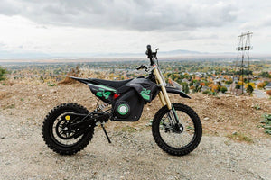 Side view of the eMOTO eBike Drift Hero 1600w dirt bike in black and green, showcasing its rugged tires, sturdy frame, and off-road design.