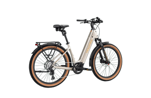 A person riding a Velotric Discover M eBike on a city street, wearing a helmet and casual clothing, with buildings and greenery in the background.