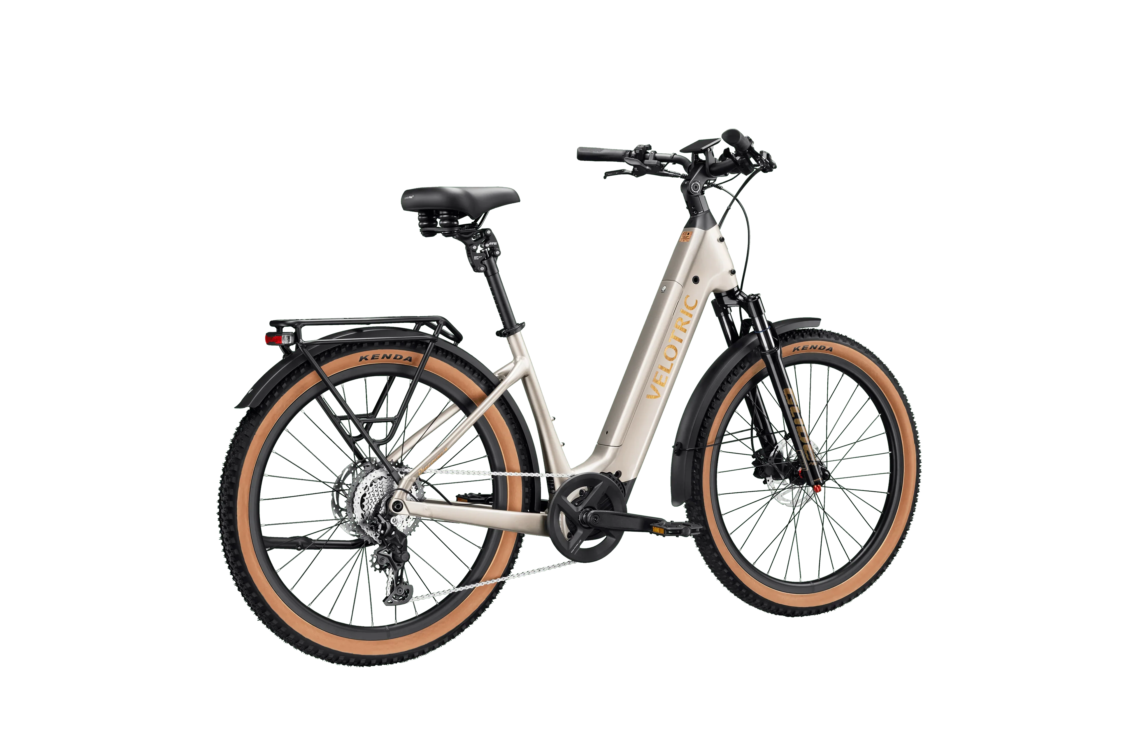 A person riding a Velotric Discover M eBike on a city street, wearing a helmet and casual clothing, with buildings and greenery in the background.