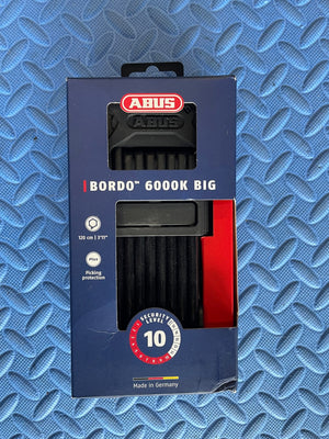 A black folding lock designed for eBikes, shown in a compact, folded position with sturdy metal links and a secure locking mechanism.