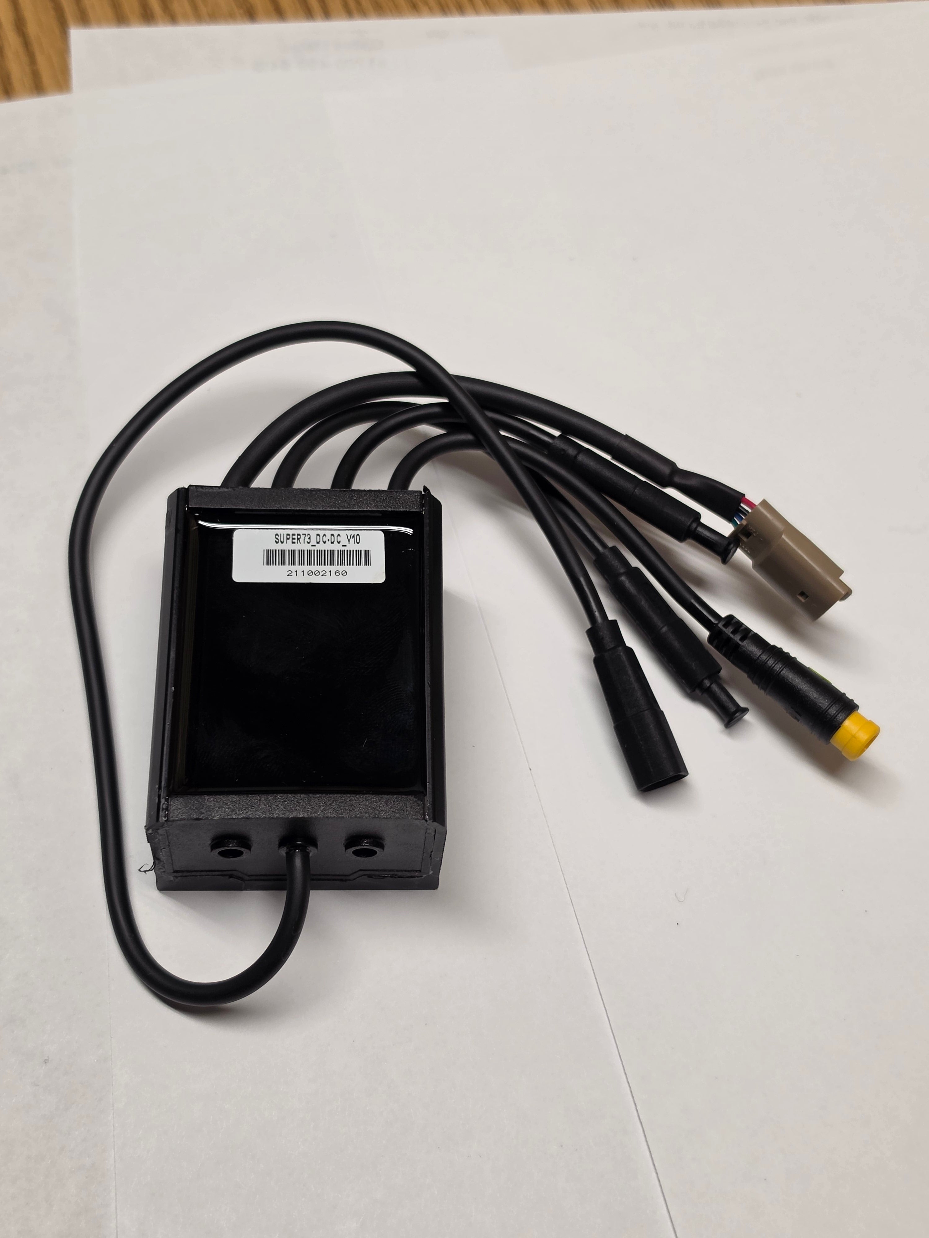 A black Super73 DCDC converter for eBikes, rectangular with labeled input and output terminals, shown on a white background.