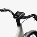 Side view of the Urtopia Carbon 1 Step Thru eBike in a modern setting, showcasing its lightweight carbon frame, step-through design, and integrated display.