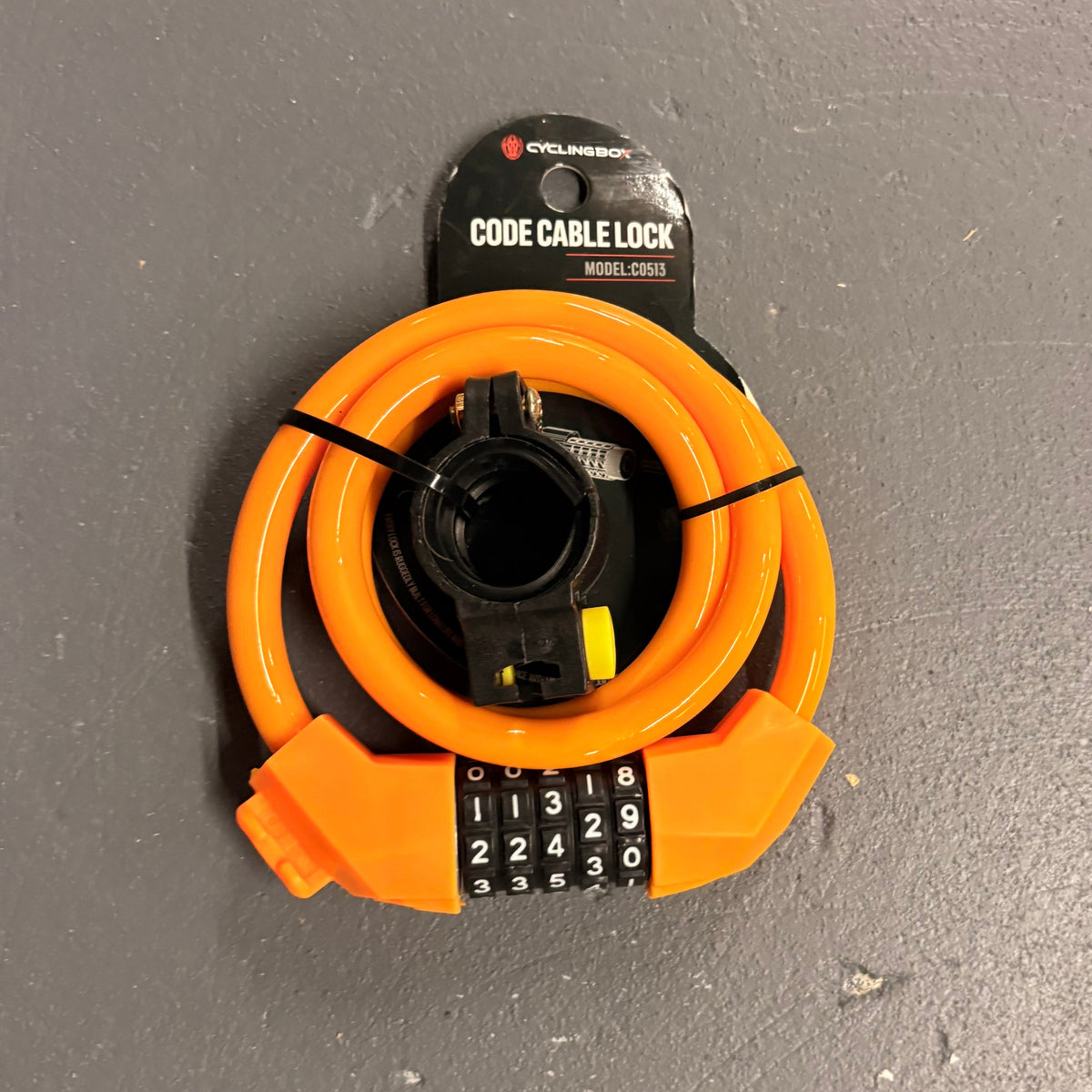 Orange cable lock with a black handle on a gray surface