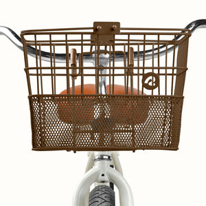 Brown Retrospec Apollo steel eBike basket attached to bicycle handlebars, shown from a side angle.
