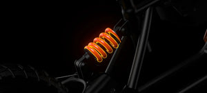 Electric bike Hyper Gogo R8 in black and orange, side view, parked on pavement with city buildings in the background.
