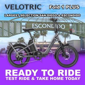 Velotric Fold 1 PLUS eBike in Stone Gray, folded and ready to ride, product image on a plain background.