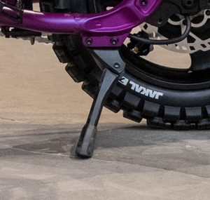 Side view of a Super73 MZFT eBike equipped with a sturdy black kickstand, displayed on a white background.