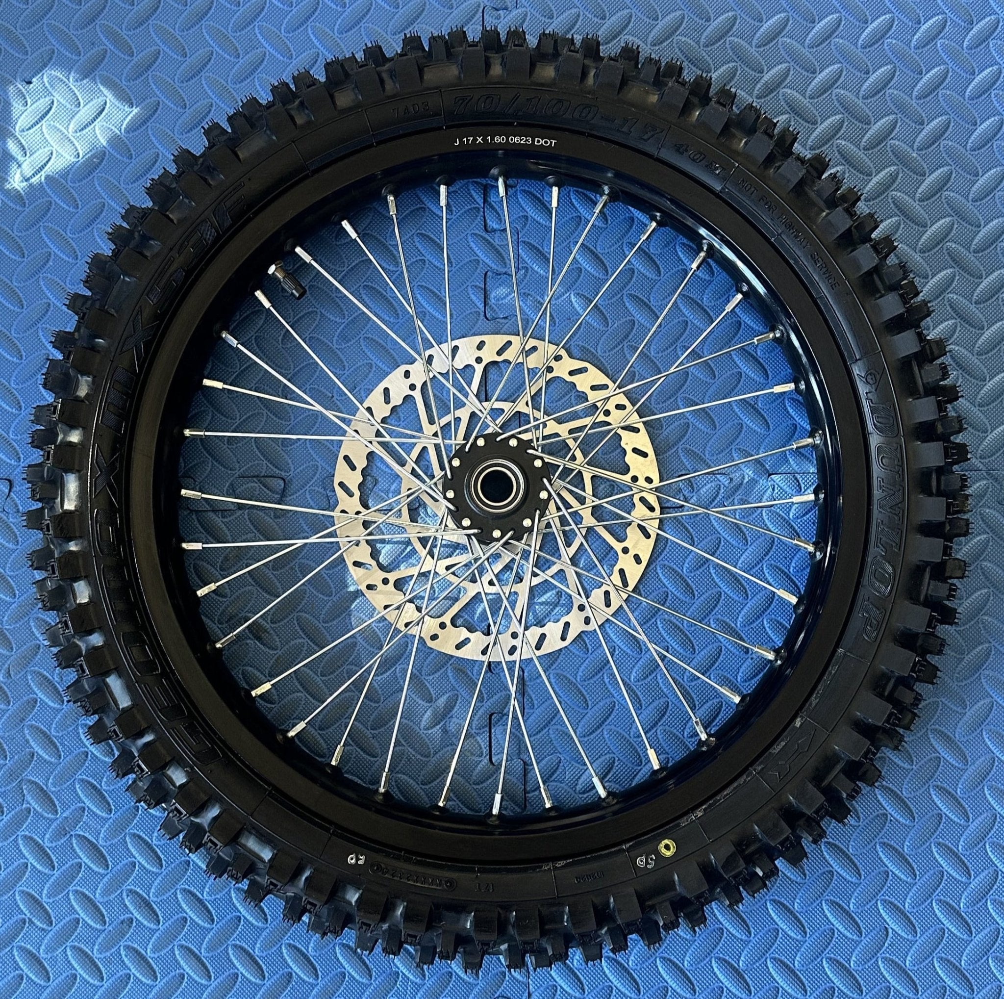 CST knobby 17-inch front wheel and tire set for Surron eMoto electric dirt bikes, shown without rotor or sprocket.