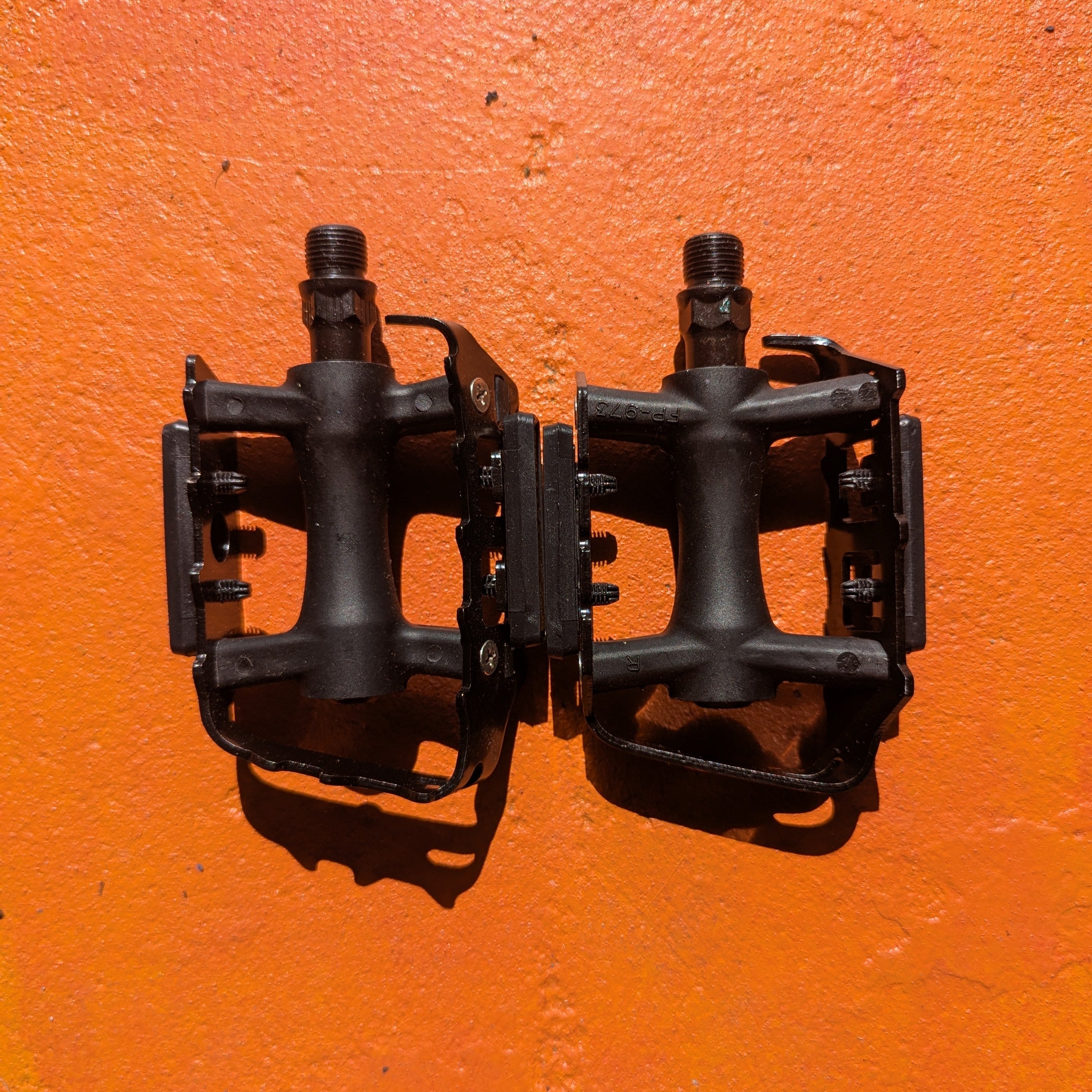 A pair of metal bicycle pedals in Style 7, featuring a sleek, durable design with textured surfaces for improved grip.