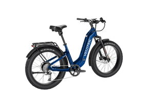 A person riding a Velotric Nomad 2 eBike on a gravel trail surrounded by trees, showcasing the bike's rugged tires and sturdy frame.