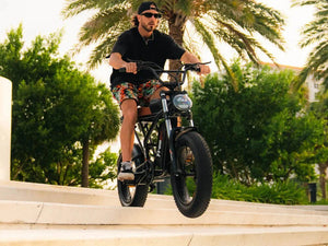 A black eMOTO FREEGO Shotgun Prime F2 Plus-Moto 1000W electric cargo e-bike with a sturdy frame, large tires, and rear cargo rack, shown from a side angle.