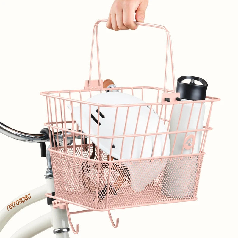 Blush pink Retrospec Apollo steel bike basket attached to an eBike, shown from a side angle.