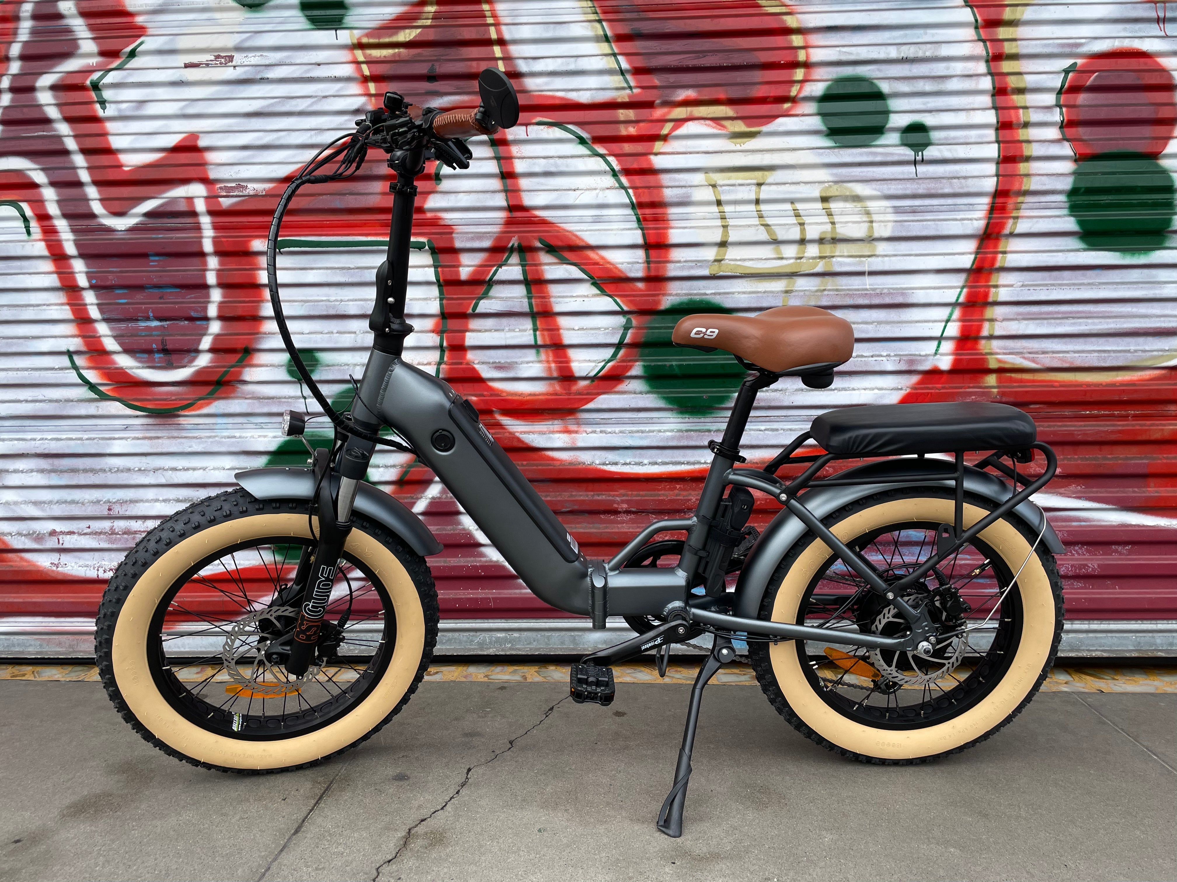 A black custom folding electric bike with a 750-watt motor, shown in a partially folded position against a white background.