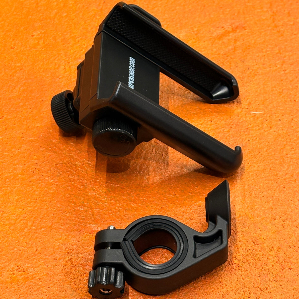 A black ebike phone mount securely attached to a bicycle handlebar, holding a smartphone in place.