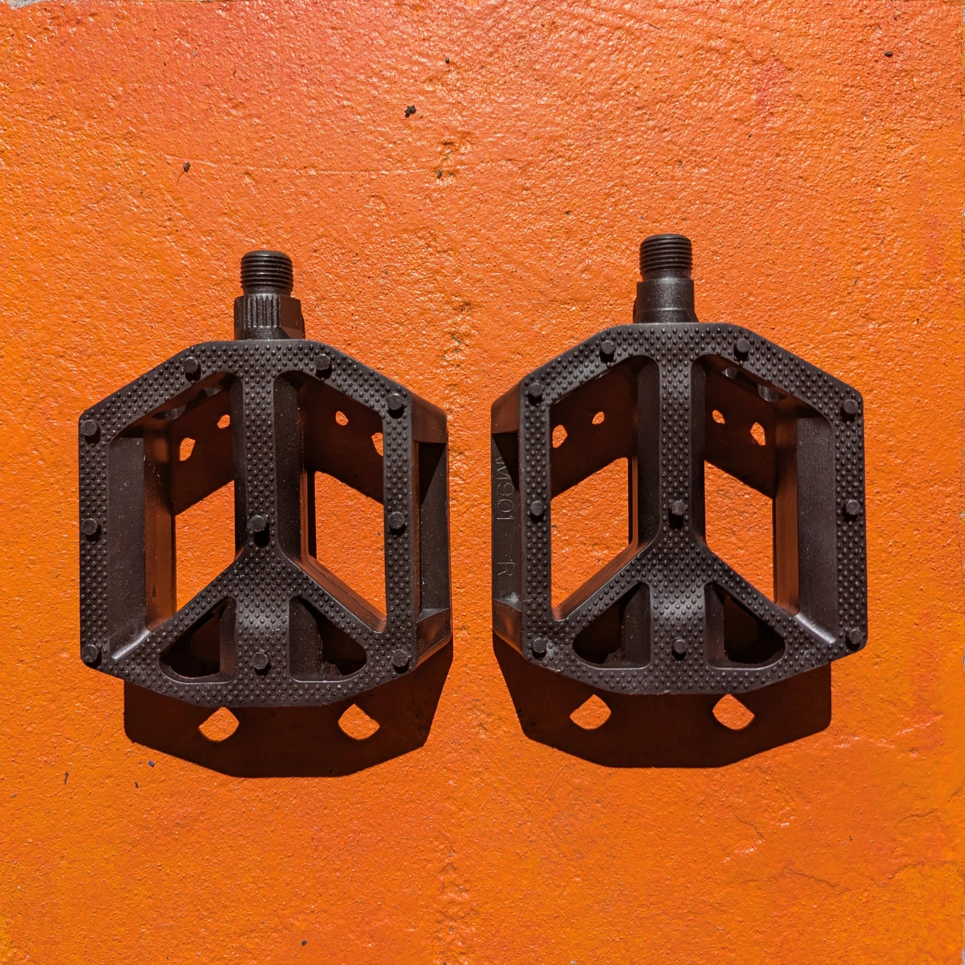 Black nylon e-bike pedals with a textured surface and wide platform design, featuring reflectors on the sides for increased visibility.