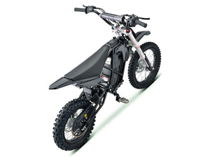Side view of the eMOTO Stomp Ebox V3 72 RS electric dirt bike in a studio setting, showcasing its frame, wheels, and suspension components.