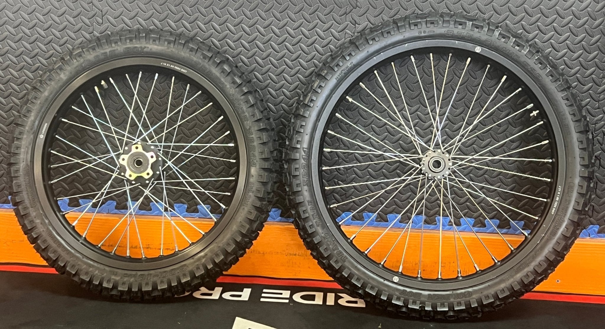 Product image of the eMOTO Surron eMoto Wheel Set featuring Shinko 244 Dual Sport 18-inch rear and 19-inch front wheels with tires, designed for moto bikes; rotors and sprockets not included.
