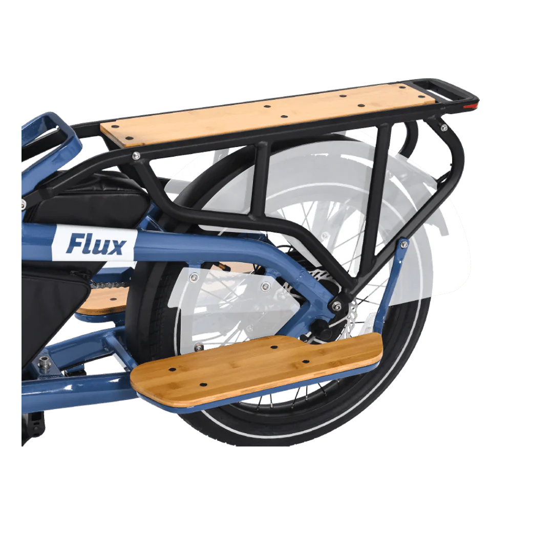 A silver eBike Revi Flux ST parked on a paved path, featuring a step-through frame, front suspension fork, and rear rack, with trees and greenery in the background.