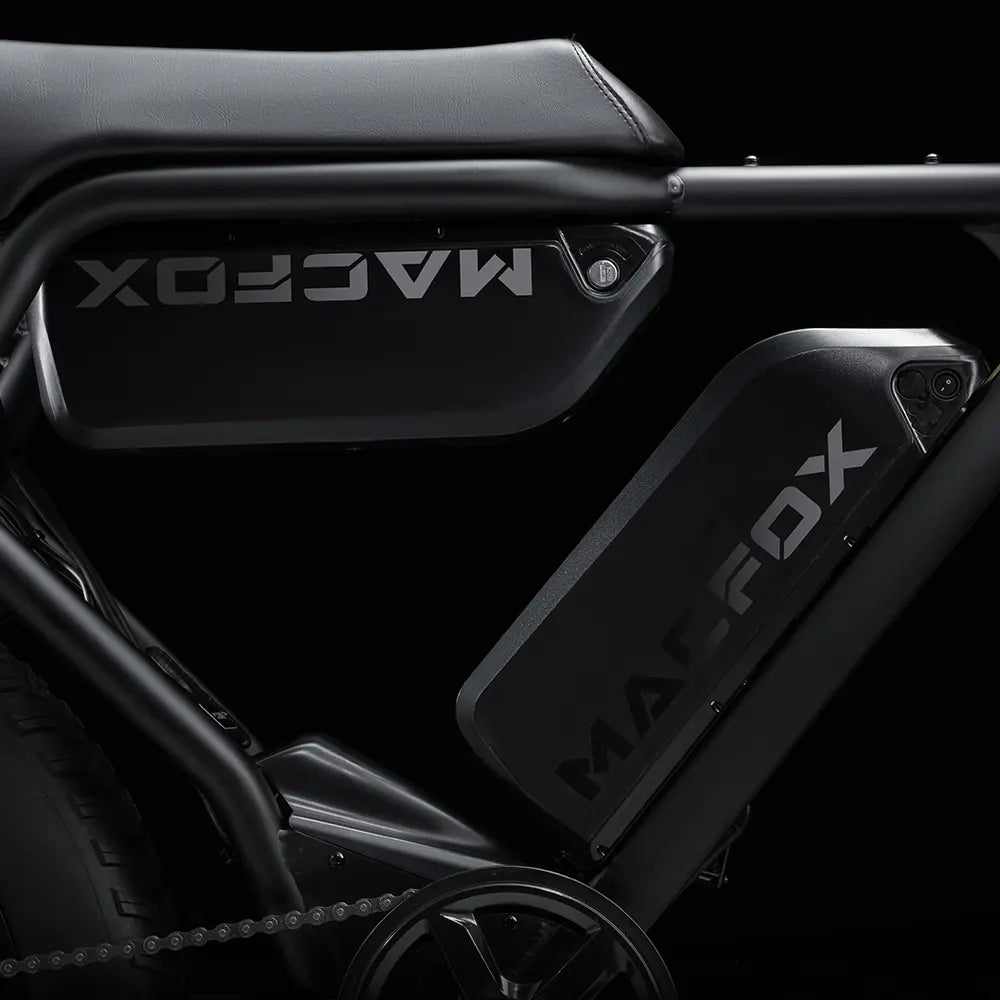 Side view of the Macfox X2 eBike in a rugged outdoor setting, showcasing its sturdy frame, fat tires, and front suspension fork.