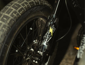 Electric bike parked outdoors, featuring a retro motorcycle-inspired design with a long seat, wide tires, and a matte black frame.
