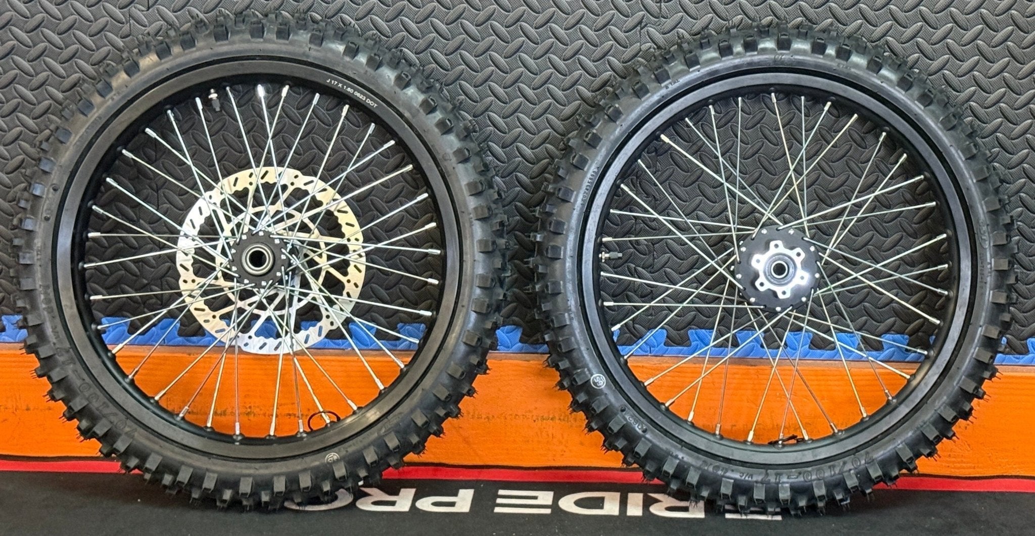 Alt text: Surron eMoto CST Knobby 19-inch front and rear wheel and tire set for electric dirt bikes, shown without rotor or sprocket.