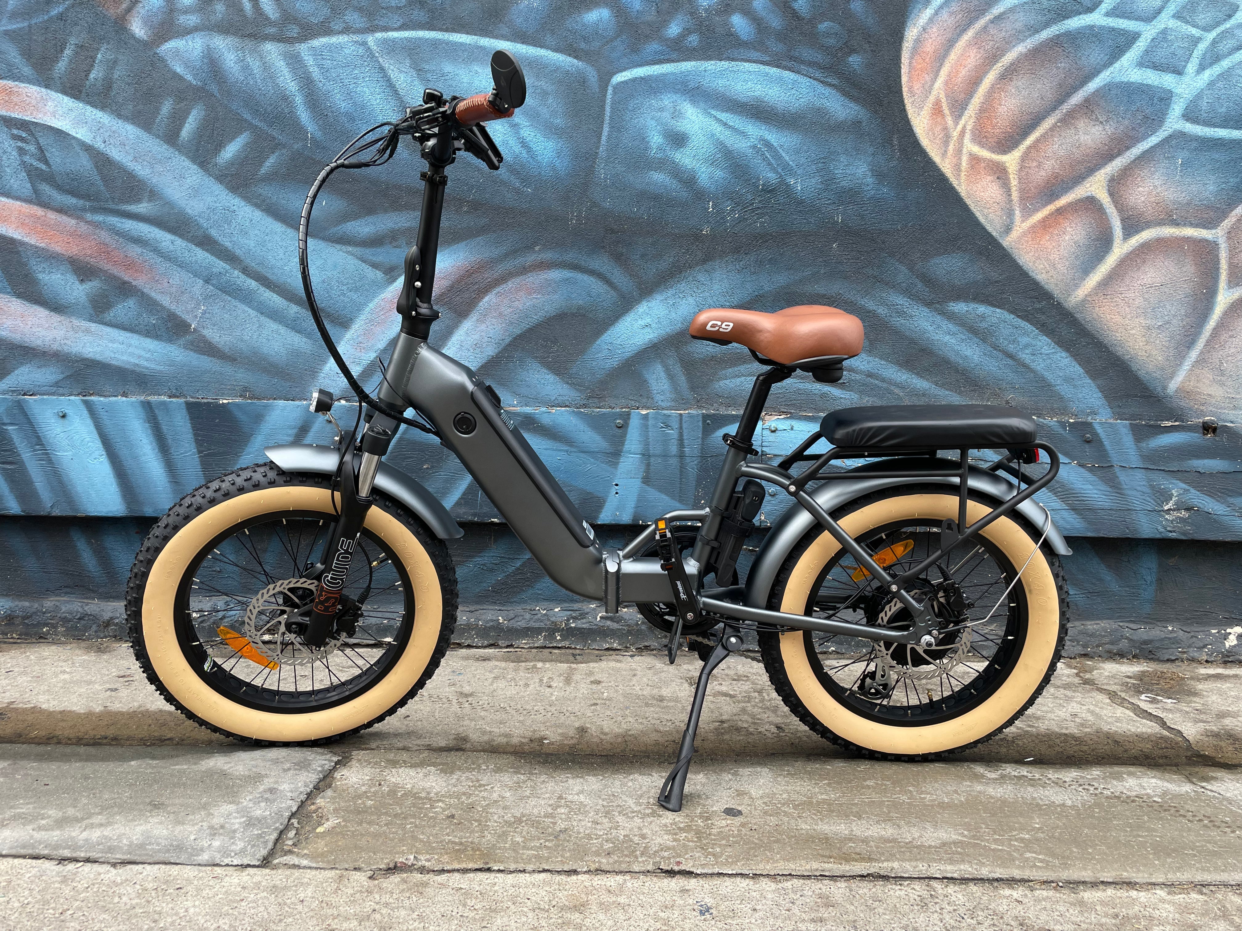A black custom folding electric bike with a 750-watt motor, shown in a partially folded position against a white background.