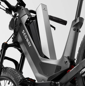 A Segway Xafari eBike parked outdoors on a gravel path, surrounded by greenery, showcasing its sturdy frame, wide tires, and integrated battery.