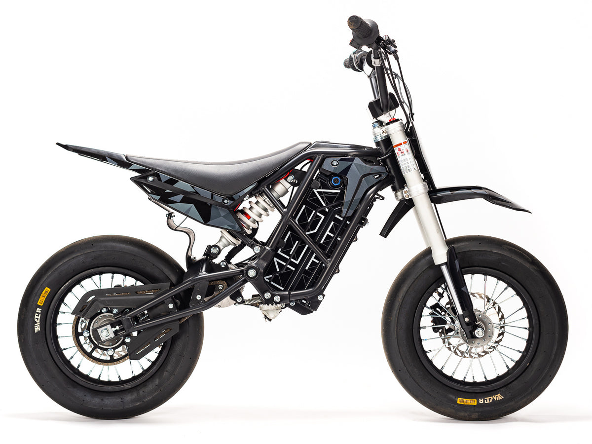 Stomp Ebox Megalith Graphics Kit displayed on a dirt bike, featuring bold geometric patterns in black, white, and neon yellow with the Stomp logo.
