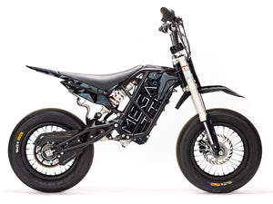 Stomp Ebox Megalith Graphics Kit displayed on a dirt bike, featuring bold geometric patterns in black, white, and neon yellow with the Stomp logo.