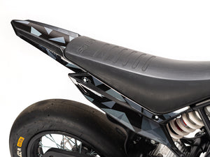 Stomp Ebox Megalith Graphics Kit displayed on a dirt bike, showcasing bold geometric patterns in black, white, and neon yellow with the Stomp logo on the side panels.