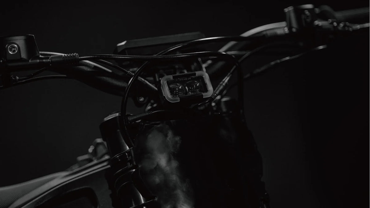 Side view of the eMOTO Tork Pro Sport electric motorcycle in a studio setting, showcasing its sleek black and blue body, aerodynamic design, and modern alloy wheels.