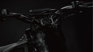 Side view of the eMOTO Tork Pro Sport electric motorcycle in a studio setting, showcasing its sleek black and blue body, aerodynamic design, and modern alloy wheels.