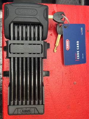 A black folding lock designed for eBikes and electric bikes, shown in a compact, folded position with sturdy metal links and a secure locking mechanism.